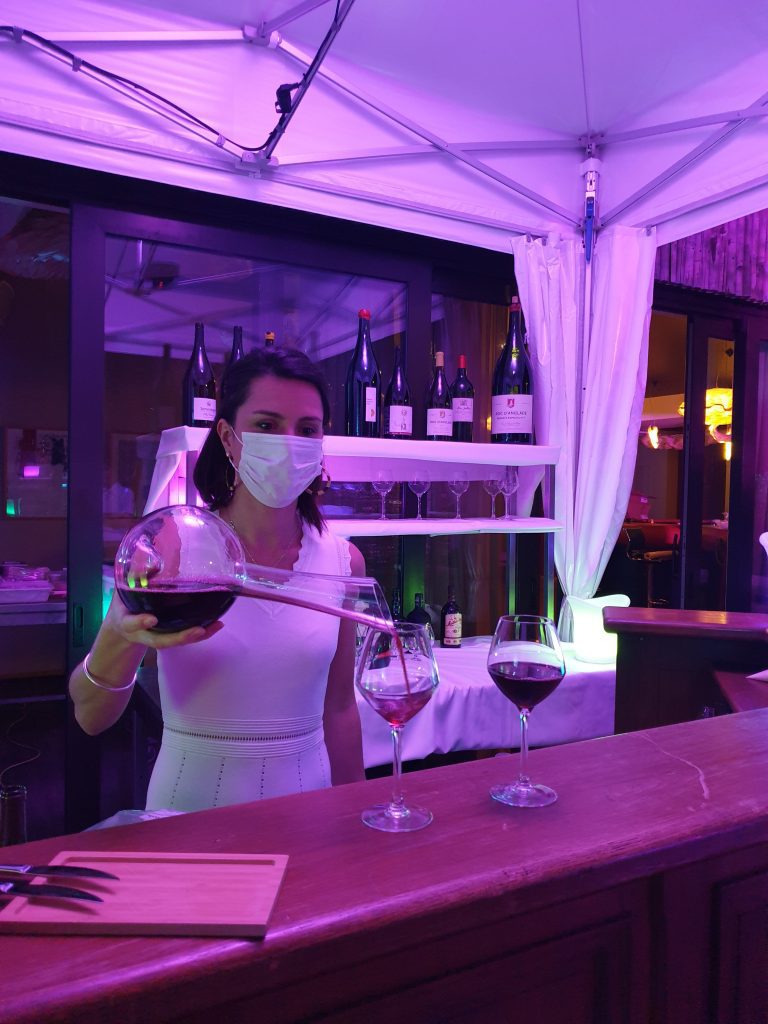 Serveuse derrière le bar sert du vin dans des verres